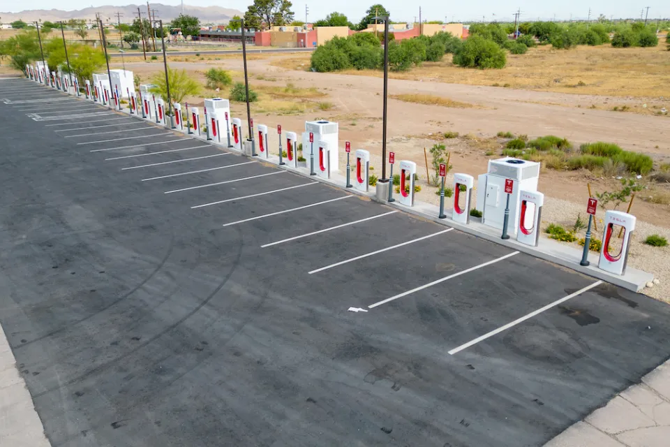 Vacant Tesla charging station in asphalt parking lot next to Interstate 10 in Arizona.